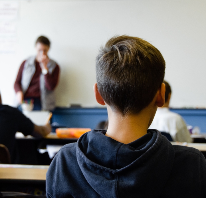 Students in classroom, teacher at front of room at whiteboard