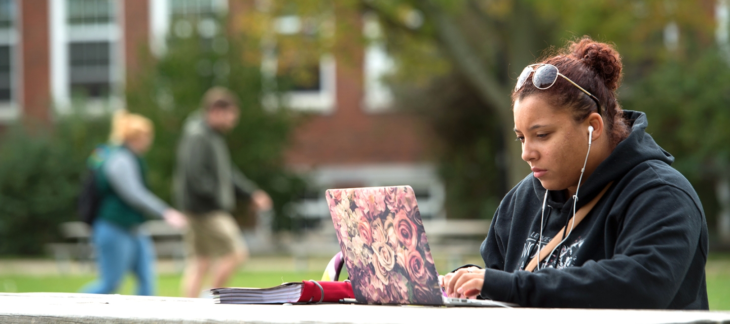 Student with a laptop at a picnic bench